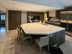 Modern kitchen with white quartz waterfall island, dark cabinetry, and stainless steel appliances