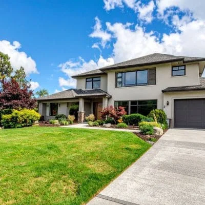 Manicured residential lawn with trimmed shrubs, flowering plants, and maintained landscape beds